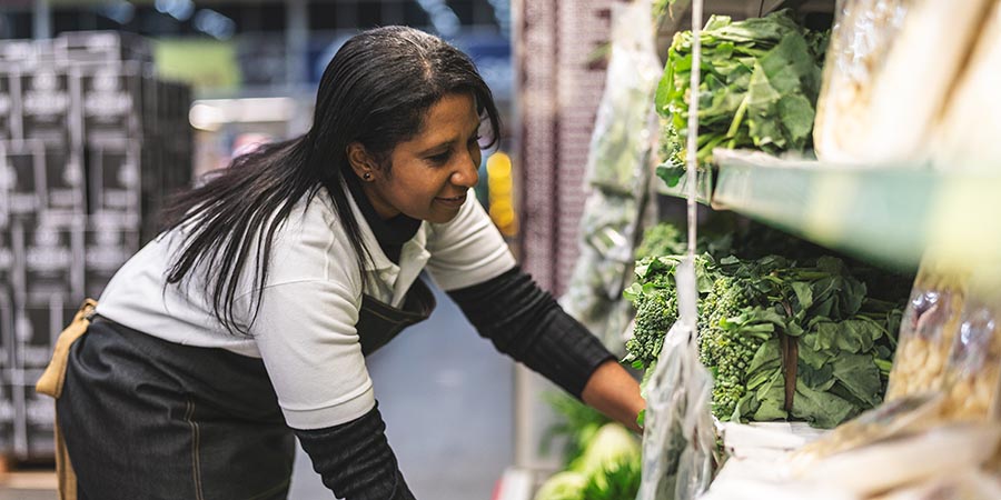 woman stocking produce at a supermarket